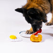 Load image into Gallery viewer, IHOP x P.L.A.Y. Eggcellent Play Platter - big fluffy brown dog pulling the bacon off the plate with the hashbrown and egg on the floor bedside its paws