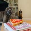 Load image into Gallery viewer, P.L.A.Y. Snack Attack Collection - Puppy-roni Pizza Toy on top of the pizza box on the coffee table with dog staring at it
