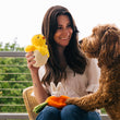 Load image into Gallery viewer, P.L.A.Y. Hippity Hoppity Collection - Chick Me Out Toy being held by dog mom while dog is perched up on her lap smiling