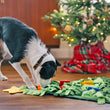 Load image into Gallery viewer, P.L.A.Y. Holiday Snuffle Mat - medium sized black and white dog nosing the tree mat in front of an actual Christmas Tree