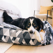 Load image into Gallery viewer, Mosaic Lounge Bed by P.L.A.Y. in Tuxedo with dog lounging in it at foot of bed
