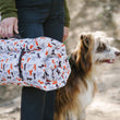 Load image into Gallery viewer, Scout & About Outdoor Chill Pad in Vanilla rolled up and being held by a human about to adventure with their dog