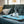 Load image into Gallery viewer, Original Chill Pad in Sea Foam with small dog lounging on it on a denim colored couch
