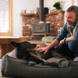 Load image into Gallery viewer, Houndstooth Lounge Bed in Shadow Gray with beautiful black dog laying in it smiling up at dog dad as he pets her