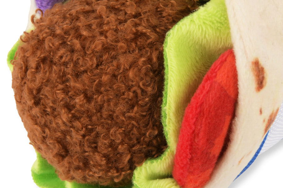 Close-up of P.L.A.Y. falafel ball dog toy with brown, green, red and beige colors on a white background