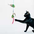 Load image into Gallery viewer, Black cat pawing the hanging feathers on P.L.A.Y. Feline Frenzy Purrfectly Pitted Wand Toy on a white background
