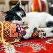 Load image into Gallery viewer, A cat playing with P.L.A.Y. Feline Frenzy Salami Slammer Kicker Toyon a red patterned rug
