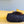 Load image into Gallery viewer, Cat curled up in P.L.A.Y. Feline Frenzy Donut Cuddler Bed - Kalahari Black on bed with yellow pillows and a blue wall in the background
