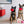 Load image into Gallery viewer, P.L.A.Y. Love Bug Collection - Smoochy Poochy Toy in two dog&#39;s mouths who are sitting in the living room looking at the camera
