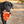 Load image into Gallery viewer, Camp Corbin Collection Cozy Campfire Toy by P.L.A.Y. being carried in mouth of black lab
