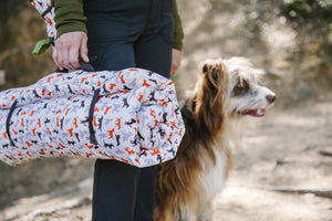 Scout & About Outdoor Chill Pad in Vanilla rolled up and being held by a human about to adventure with their dog