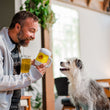 Load image into Gallery viewer, P.L.A.Y. Hollywoof Cinema Hoppy Hound Brew Toy - dog dad holding a beer and the beer toy presenting to a white small dog looking up smiling back
